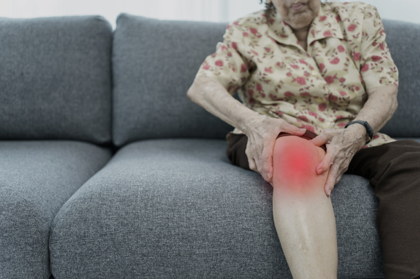 Asian elder woman having a critical health problem at knee and bone joint, woman touching or holding at knee. Elder woman getting hurt and injured at her leg. - Fotó, kép