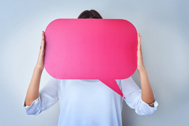 People with the biggest voices online never show their face. an unrecognizable woman holding up a speech bubble against a blue background - Foto, afbeelding
