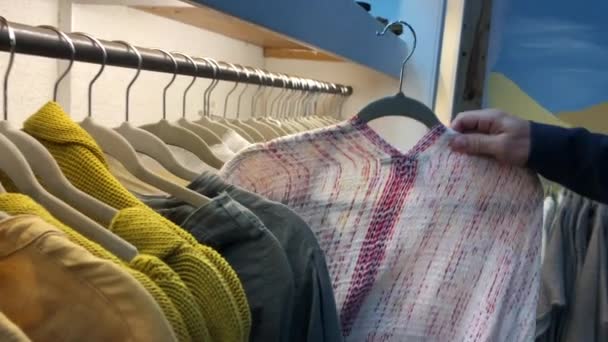 Woman pulling clothing from hanger - Materiał filmowy, wideo