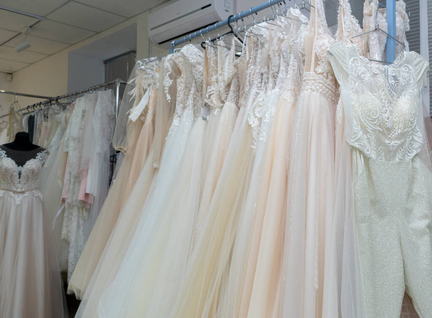 White and cream wedding dresses on a hanger in a bridal boutique. Close up. - Photo, image