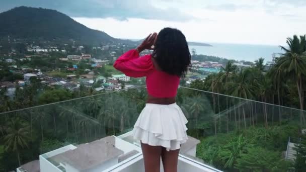 Steadicam shot of African woman on balcony, enjoying an amazing view of tropical Asian nature on rainy and overcast day - Metraje, vídeo
