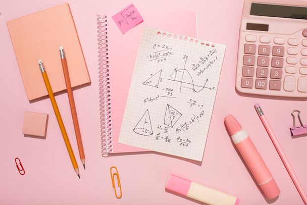 On a pink background, pink school supplies, a calculator, cheat sheets. High quality photo - Photo, image