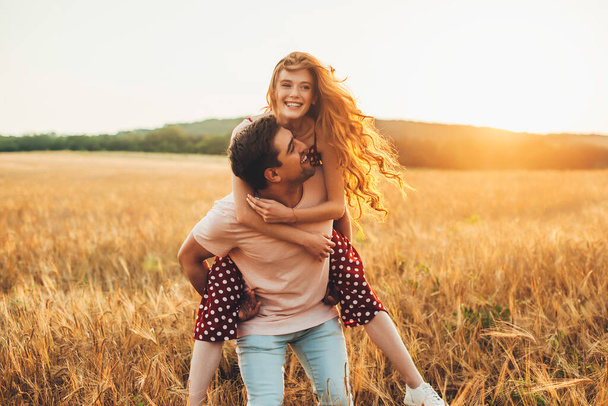 Caucasian man giving the girl a piggy back ride as they smile at the camera while enjoying a day in the country. Harvesting agriculture and plantation concept - Photo, image