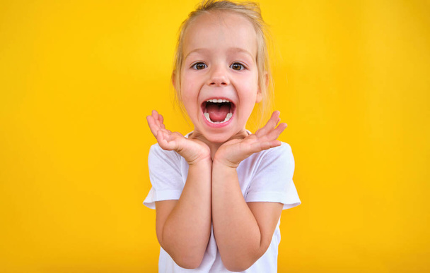 Fröhliches, fröhliches kleines Mädchen lächelt und zeigt vereinzelt die Daumen nach oben auf gelbem Hintergrund. Hochwertiges Foto - Foto, Bild