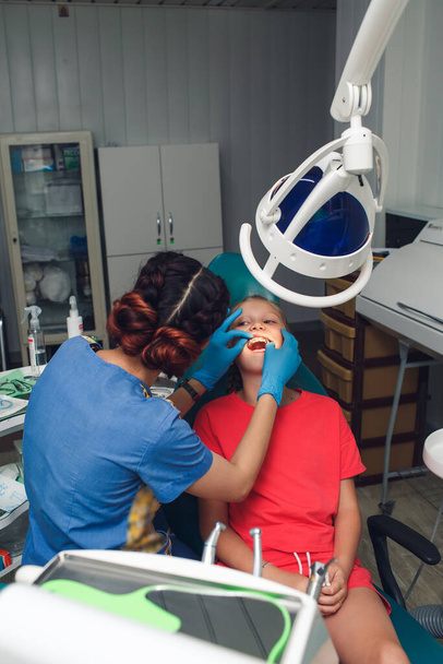 Orthodontist examining dental braces in a teenager girl - Foto, afbeelding
