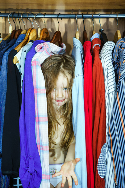 Cute little girl hiding inside wardrobe from her parents - Photo, Image
