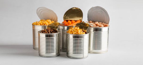 Open tin cans with different food on light background - Fotoğraf, Görsel