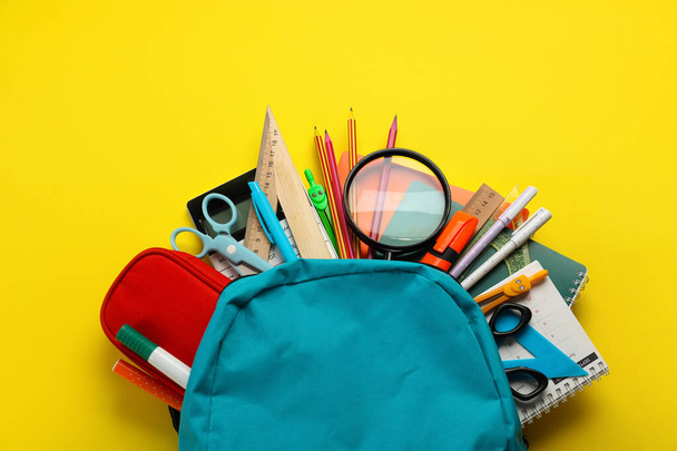 School backpack with stationery supplies on yellow background - Photo, Image