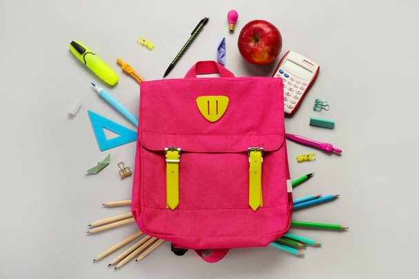 School backpack with stationery and apple on grey background - Foto, afbeelding