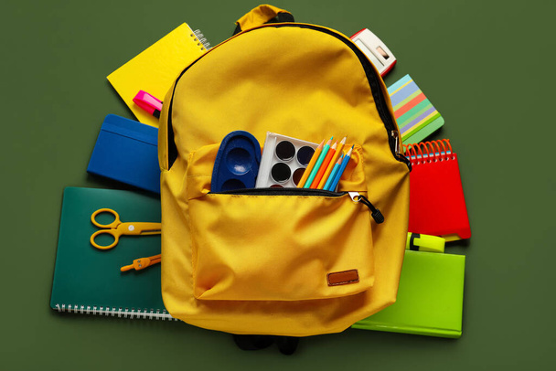 Yellow backpack with school stationery on green background - Foto, immagini