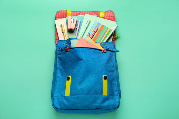 Blue backpack with school stationery on green background - Fotoğraf, Görsel