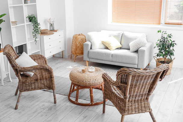 Интерьер уютной гостиной с креслами из ротанга и столом - Фото, изображение