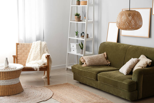 Интерьер уютной гостиной с ротанговым столом, креслом и зеленым диваном - Фото, изображение