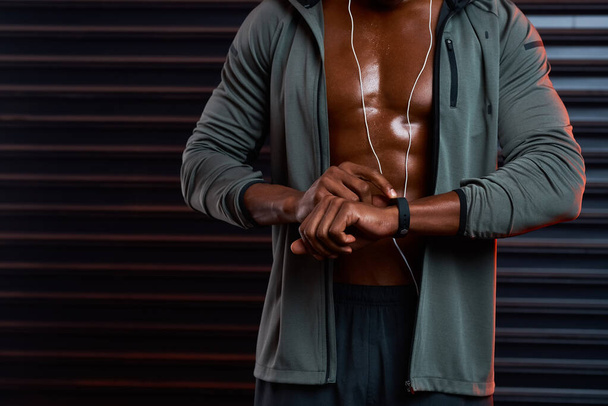 Timing yourself is crucial when youre working out. Studio shot of an unrecognizable male athlete looking at his wrist watch against a grey background - Photo, image