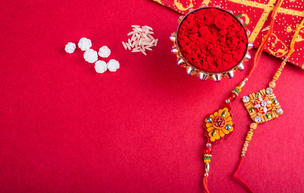 Παραδοσιακά ινδικά κοσμήματα με ρύζι, μπαχαρικά και ευχετήρια κάρτα σε κόκκινο φόντο - Φωτογραφία, εικόνα