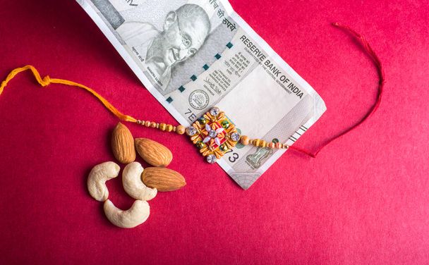 Traditional Indian jewelry with peanuts and money banknotes on red background - Photo, image