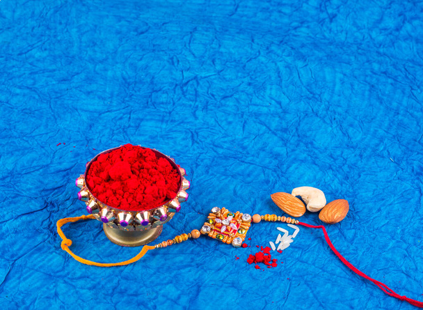 Traditional Indian jewelry with rice, spice and peanuts on blue background - Fotografie, Obrázek