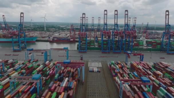 Slider of machinery in harbour cargo terminal. Aerial view of stacked overseas containers and majestic gantry cranes loading large ships. Intermodal transport and global logistics. Hamburg, Germany. - Video