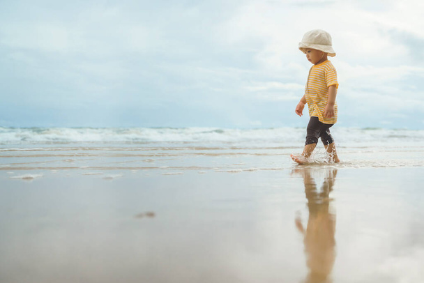 Asian boy walking on the beach. Adorable child in outdoor summer holiday vacation - Photo, image