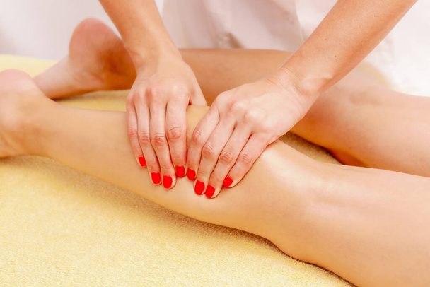 Young woman getting a massage at the spa. Body care. Therapeutic foot massage in the spa salon. Skin care, well-being. - Foto, Imagem