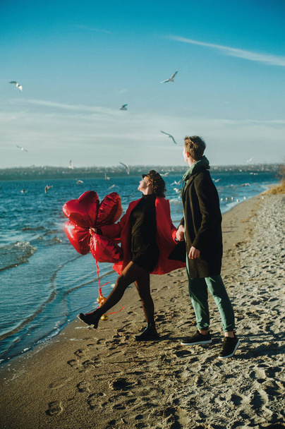 Happy running couple with a red heart balloons on the beach - Foto, immagini