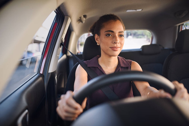 Smiling business woman driving car in city streets. Happy african american woman feeling comfortable sitting on driver seat in her new car. Mixed race girl with seat belt driving vehicle. - Valokuva, kuva