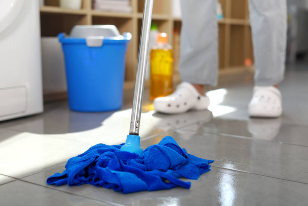 Woman washing floor at home, she is using a mop and wiping tiles - Photo, Image