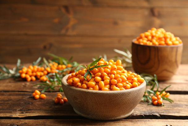 Fresh ripe sea buckthorn in bowl on wooden table. Space for text - Valokuva, kuva