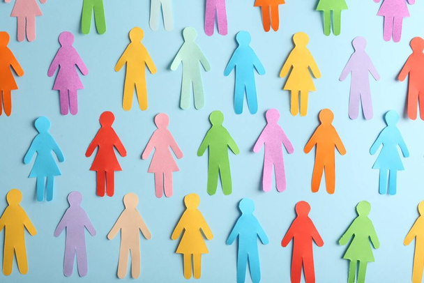 Many different paper human figures on light blue background, flat lay. Diversity and inclusion concept - Foto, afbeelding