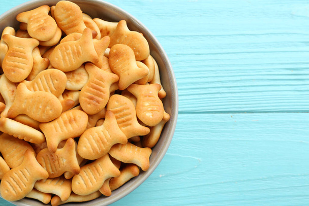Delicious goldfish crackers in bowl on light blue wooden table, top view. Space for text - Photo, image