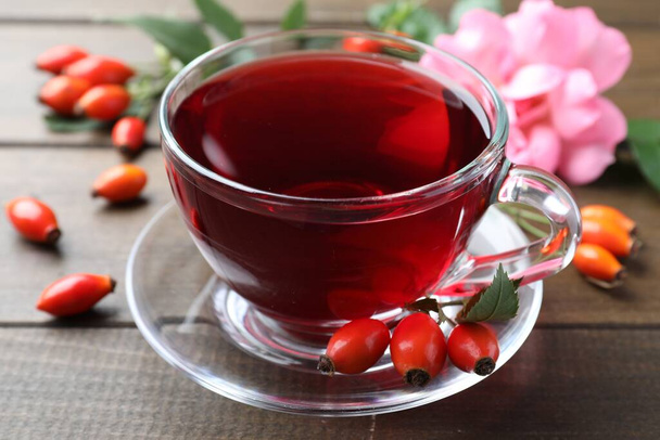 Aromatic rose hip tea and fresh berries on wooden table, closeup - Foto, Imagem