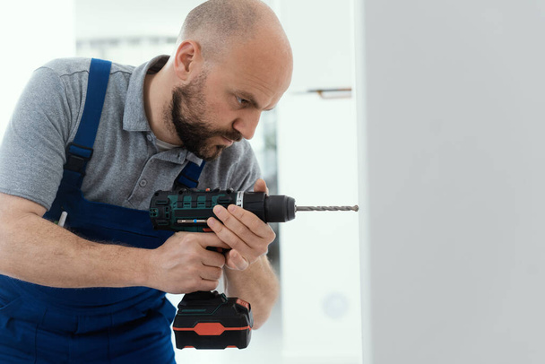 Professional handyman using a drill and drilling a hole in the wall - Fotografie, Obrázek