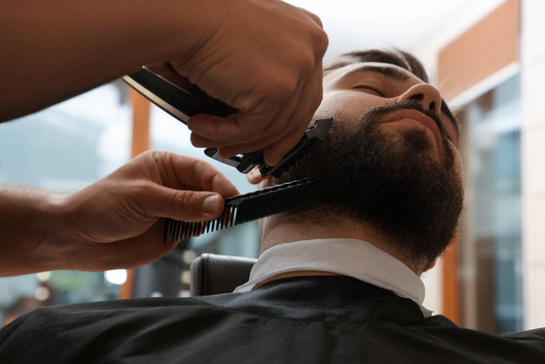 Professional hairdresser working with client in barbershop, closeup - 写真・画像