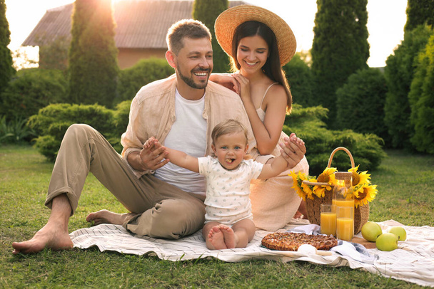 Happy family having picnic in garden on sunny day - Фото, изображение