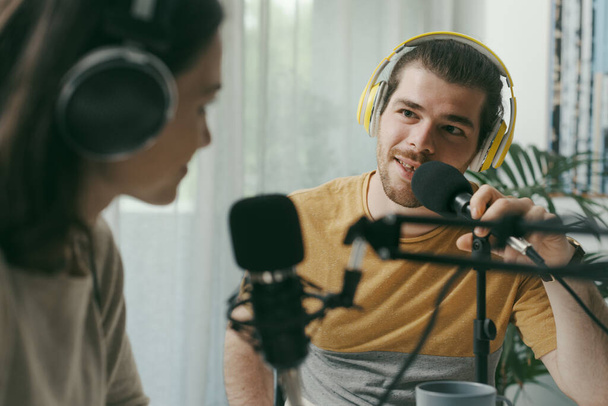 Young man and woman wearing headphones and doing a live podcast for their channel, communication and technology concept - Photo, image