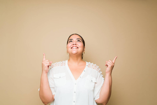 Studio portrait of a smart obese woman smiling having a great idea while thinking and using her imagination  - Photo, image