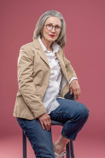Elegant woman. Elegant mature woman in beige jacket sitting on a chair - Фото, зображення