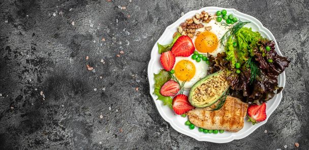 Υγιεινή διατροφή paleo keto πρωινό διατροφή Τηγανητά αυγά, αβοκάντο, ψητό φιλέτο κοτόπουλου, ξηρούς καρπούς, φράουλες και φρέσκια σαλάτα. Πρωινό ή μεσημεριανό. Μεγάλη μορφή πανό. πάνω όψη, - Φωτογραφία, εικόνα