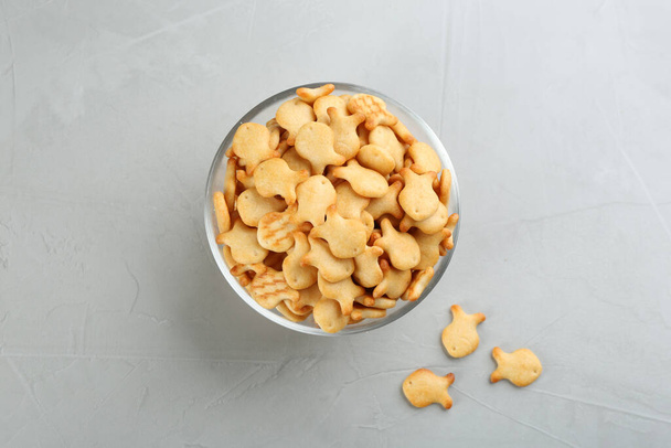 Delicious goldfish crackers in bowl on grey table - Photo, image