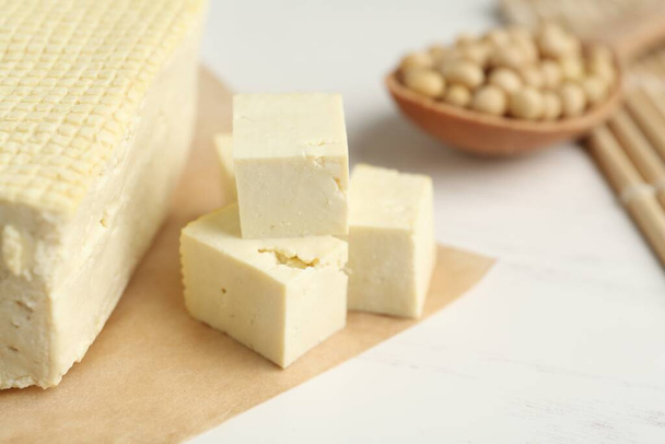 Cut tofu and soya beans on white wooden table, closeup - Photo, image