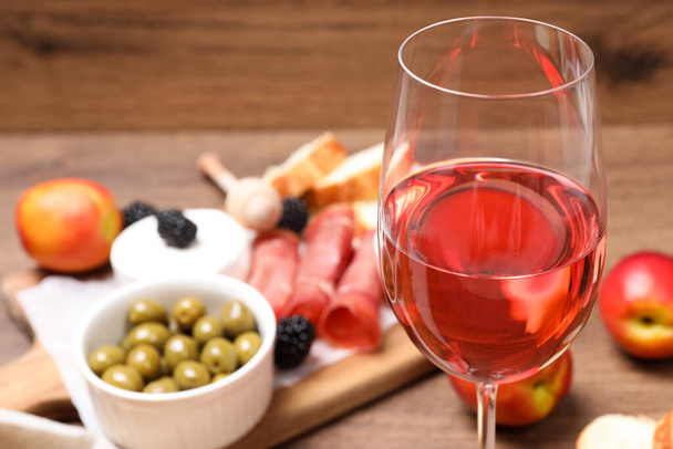Glass of delicious rose wine and snacks on table, closeup - Foto, Imagem