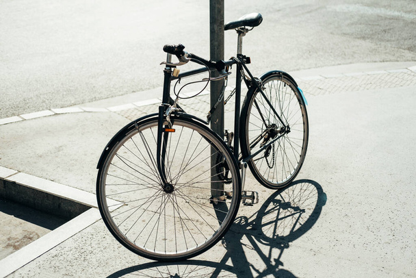 Μια φωτογραφία ενός ποδηλάτου ακουμπισμένη σε ένα στύλο έξω. - Φωτογραφία, εικόνα