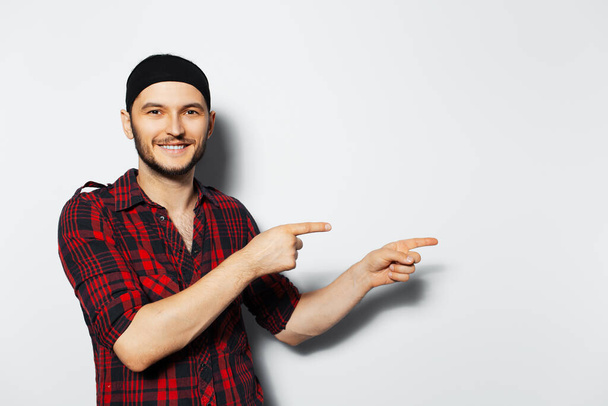 Studio portrait of young smiling guy, pointing to the left. Copy space idea. - Photo, image