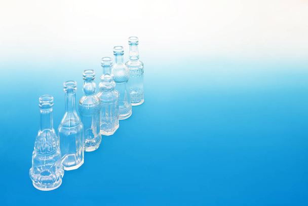 Старі скляні пляшки в діагональній лінії на градієнтному синьому білому фоні. Ретро абстрактна тема концепція креативного дизайну
. - Фото, зображення