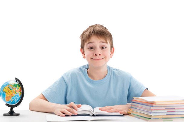 Усміхнений хлопчик-підліток сидить за столом зі стопкою ноутбуків, які роблять домашнє завдання. Освіта за кордоном концепція. Міжнародна освіта
 - Фото, зображення