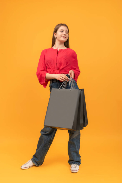 Young smiling woman after shopping keeps large paper bags. Mock up. Black Friday shopping. Vertical frame - Fotografie, Obrázek