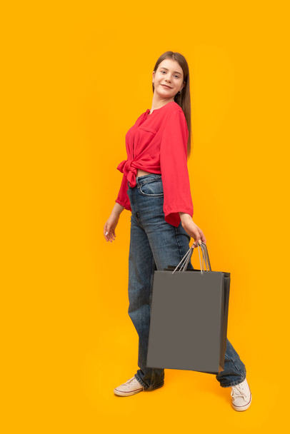 Посмішка підліткової дівчини з сумками після покупки на жовтому тлі. Жінка з сумками. Пристебніться. Копіюю простір. Чорна п "ятниця - Фото, зображення
