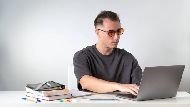 Estudiante masculino escribiendo en la computadora portátil en el escritorio. Foto de alta calidad - Foto, imagen