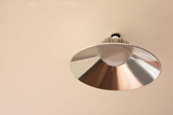 Silver ceiling lamp mounted on a cream colored ceiling - Fotoğraf, Görsel
