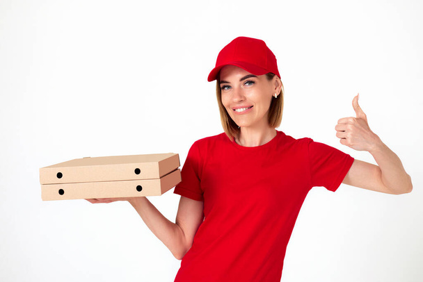 friendly pizza delivery woman in uniform with pizza boxes showing thumbs up on white background - Fotó, kép